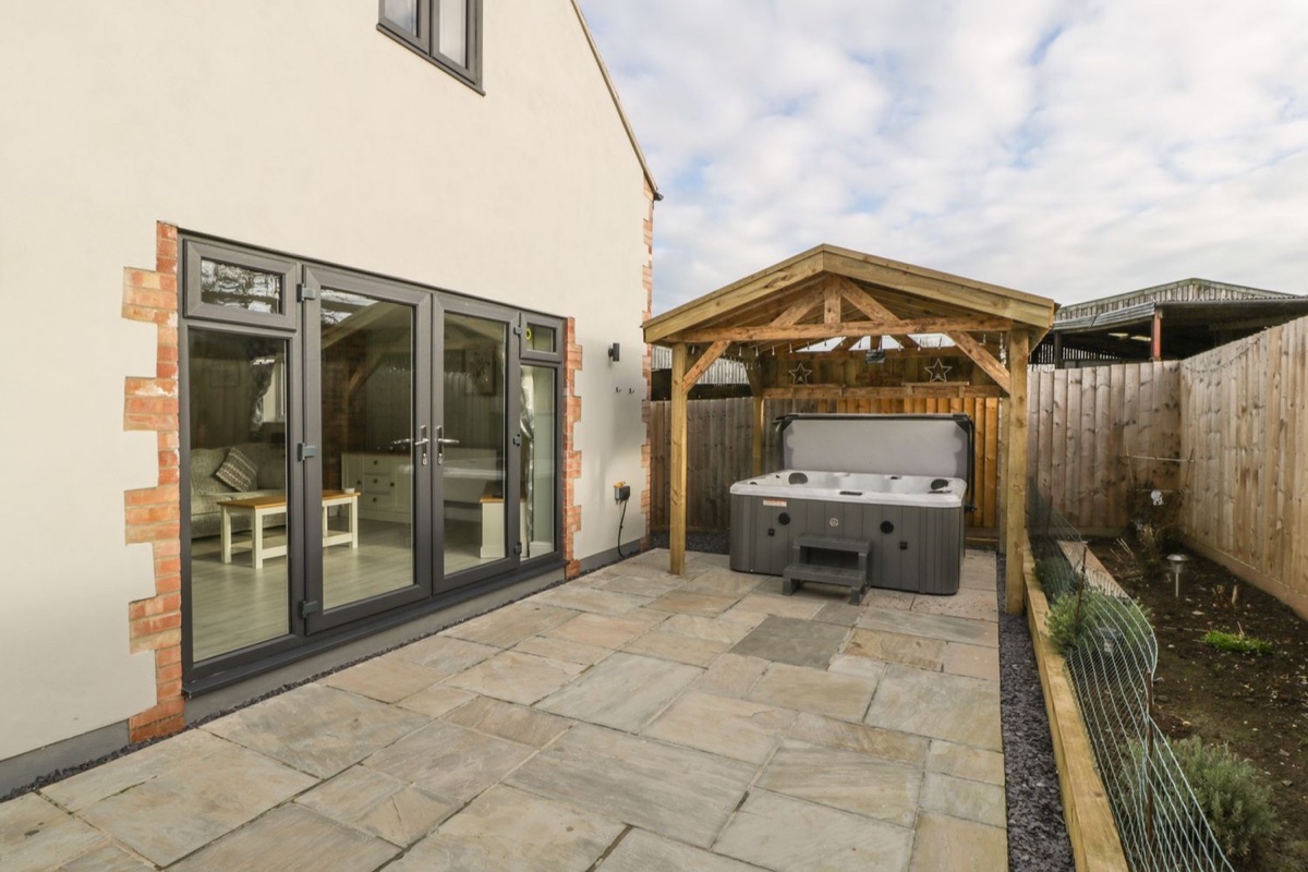 Bramley Cottage hot tub under a wooden pergola in Henley