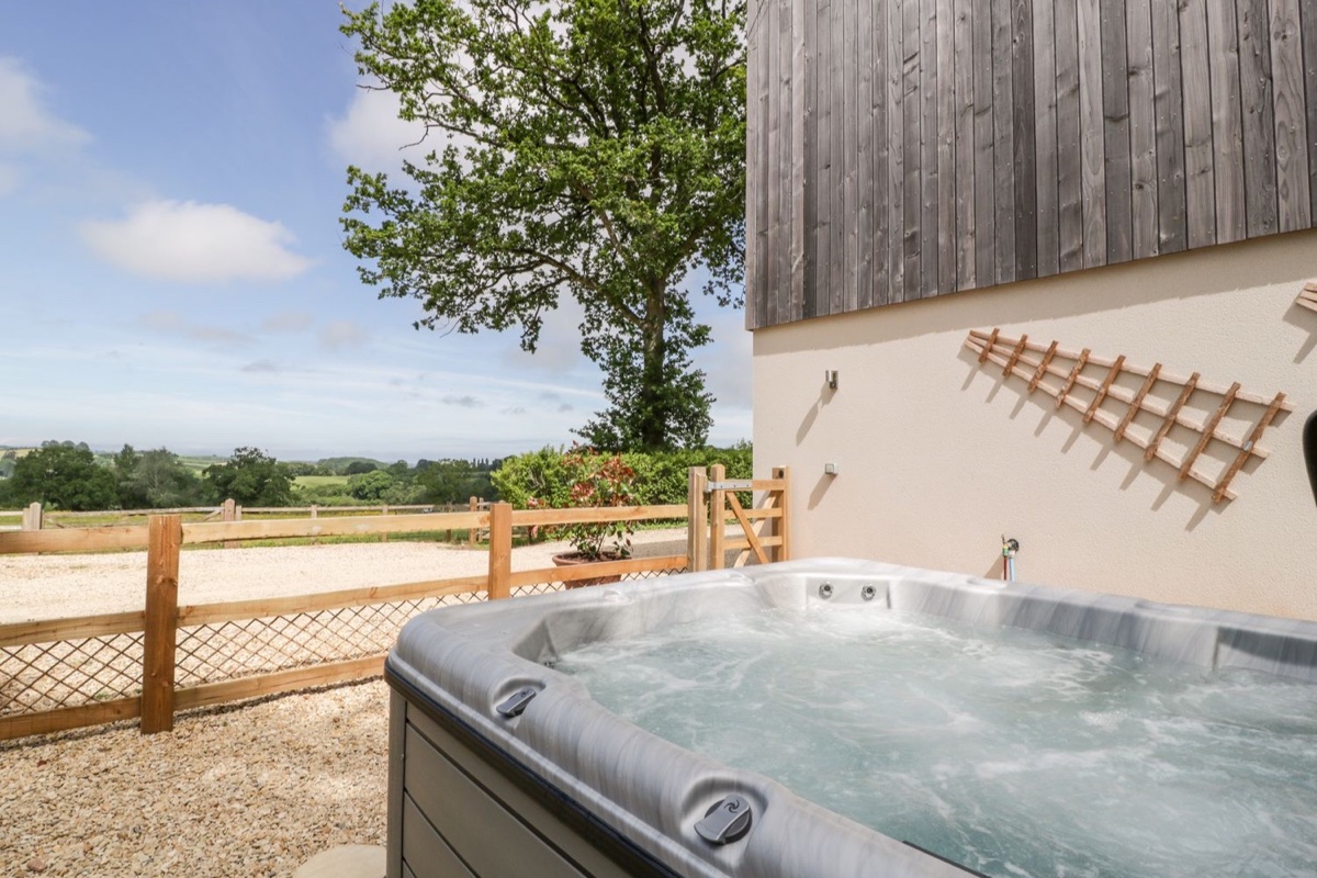 A private hot tub on a patio looking out over open countryside